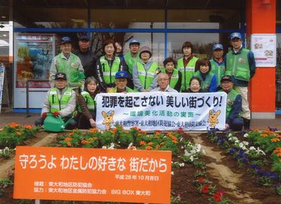 花壇の前で横断幕と共に並ぶ防犯協会の皆さんの写真