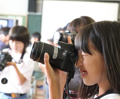 一眼レフカメラを構える女子児童の写真