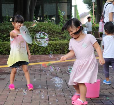 うちわでシャボン玉を作って楽しむ女の子たちの写真