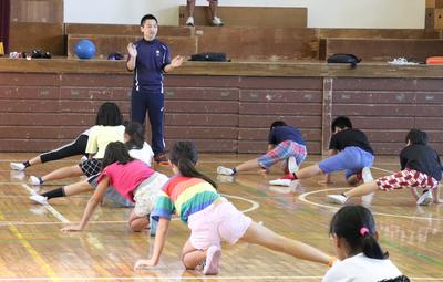 子どもたちへゴールボールのディフェンスの指導を行う川嶋さんと子どもたちの写真