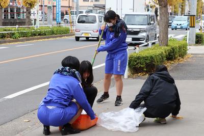 歩道を掃き掃除する東大和高校の生徒の写真