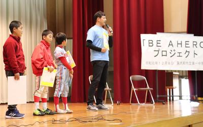 ステージ上に並ぶ子どもたちと岩隈選手の写真